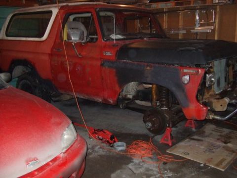 1979 Ford Bronco - Ford Bronco in a garage with its front wheel removed and suspension exposed, undergoing maintenance.