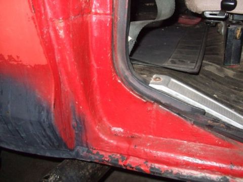 1979 Ford Bronco - Interior view of a red vehicle's door frame, showing wear and rust on the lower edge.