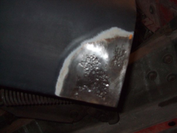 close-up of a rusty metal panel with primer and some pitting