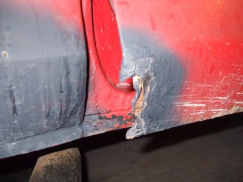 1979 Ford Bronco - Close-up of a heavily rusted vehicle rocker panel, showing damage and undercoating.