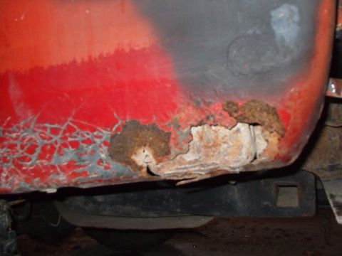 1979 Ford Bronco - The lower body panel of a vehicle shows significant rust damage and cracking paint.