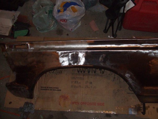 Rusty car fender with primer patches, viewed from the side