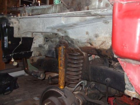 1979 Ford Bronco - Close-up view of the front suspension and frame of a vehicle, with a red fender on the right side.