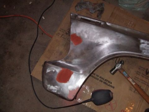 1979 Ford Bronco - A bare metal fender section, likely undergoing repair or preparation, is shown with red primer spots and a hammer nearby.