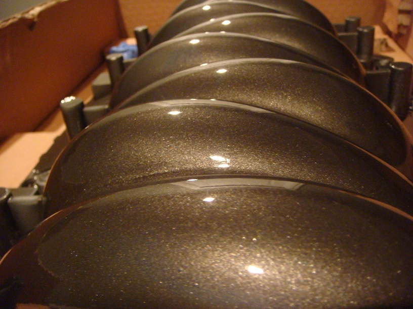 row of shiny, metallic brown engine intake manifold runners in a box