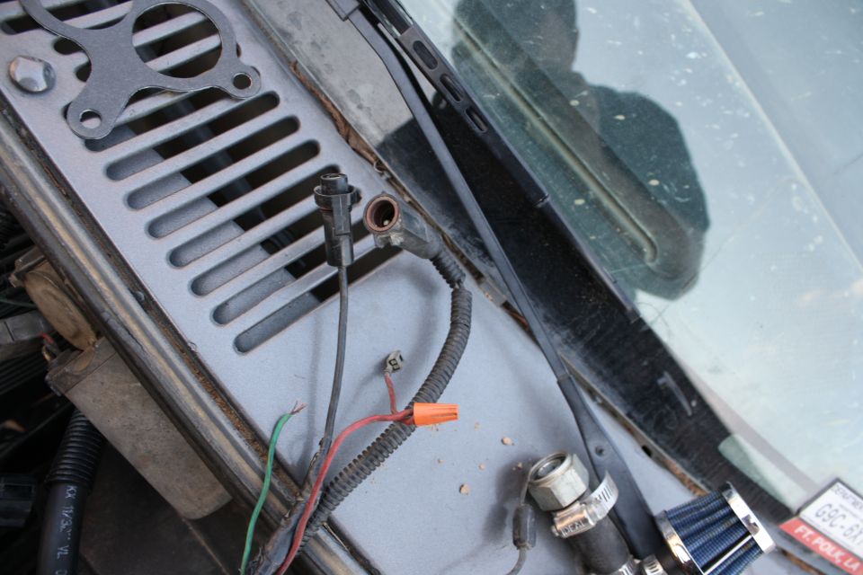Wiring pigtail with orange wire nut lying on a truck cowl vent panel