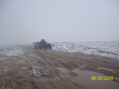 1986 Chevrolet Blazer - Two people ride an ATV on a muddy and snowy hill under a foggy sky.