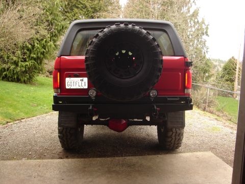 1989 Ford Bronco - Rear view of a red 1989 Ford Bronco, a spare tire on the tailgate and an aftermarket bumper.