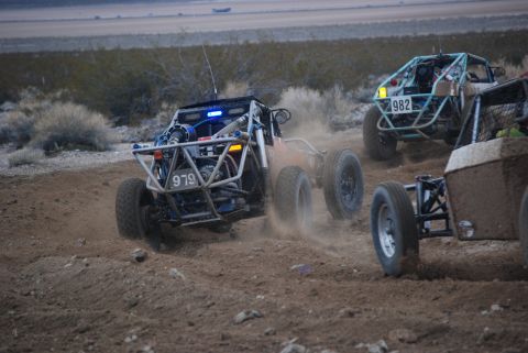 1982 Ford Bronco - Multiple off-road buggies race across a dusty, arid landscape.
