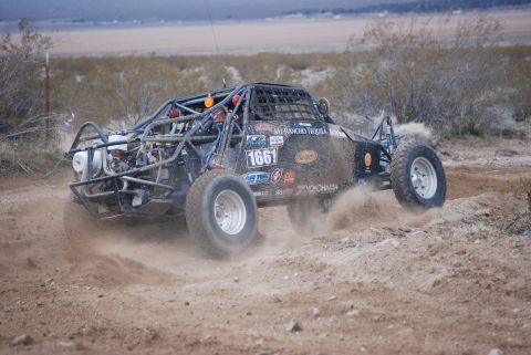 1982 Ford Bronco - A custom off-road buggy navigates a dusty track in a desert landscape.