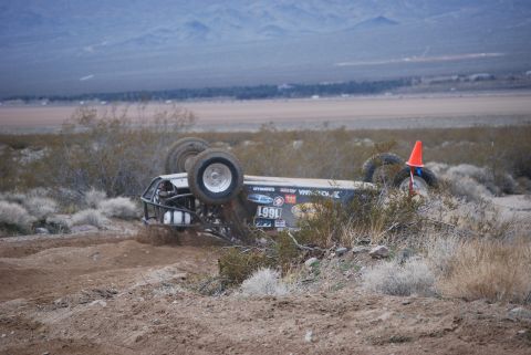 1982 Ford Bronco - An off-road buggy has rolled onto its side during a race in a desert environment.