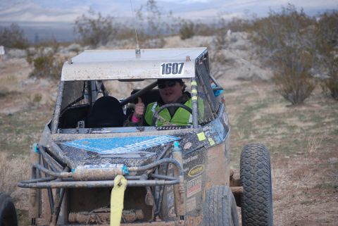 1982 Ford Bronco - A driver in a dirt-covered off-road buggy gives a thumbs-up while participating in a race.