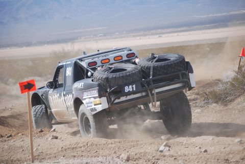 1982 Ford Bronco - A modified truck navigates a dusty off-road course, marked with the number 841 and equipped for desert racing.