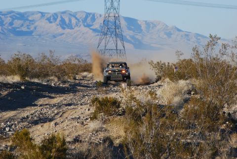 1982 Ford Bronco - A modified truck races through a dusty desert landscape near a power line tower.