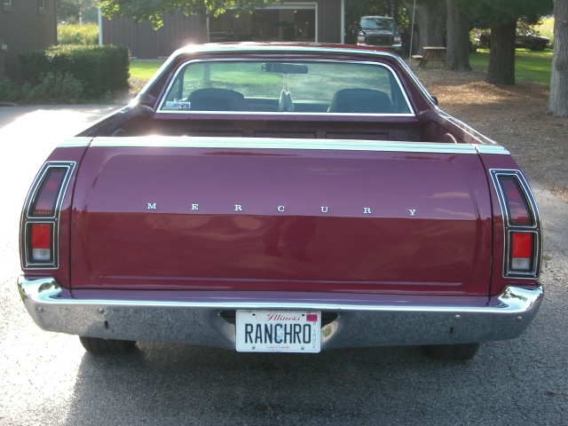 Maroon Mercury Ranchero pickup truck, rear view. Illinois plate says RANCHRO. Another vehicle is parked in driveway behind it