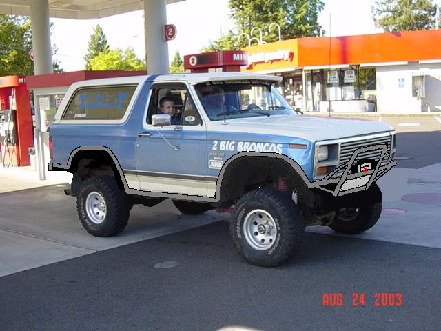 Lifted blue and white Ford Bronco with 2 BIG BRONCOS decal and tube bumper at a gas station