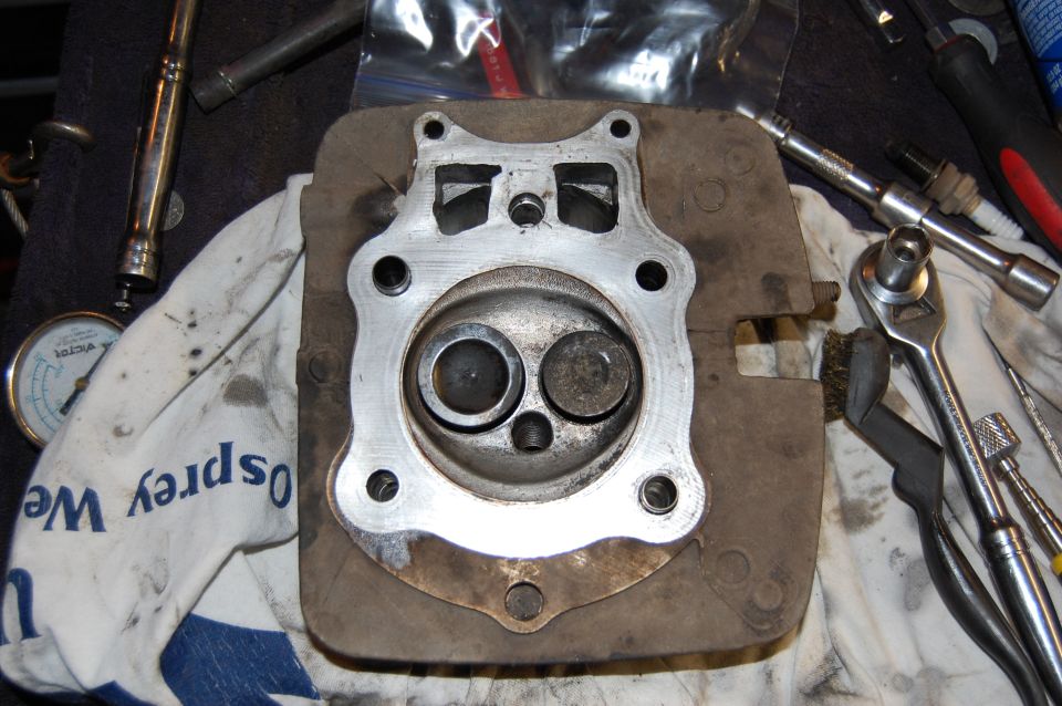 Single-cylinder ATV cylinder head on workbench, combustion chamber and valves exposed