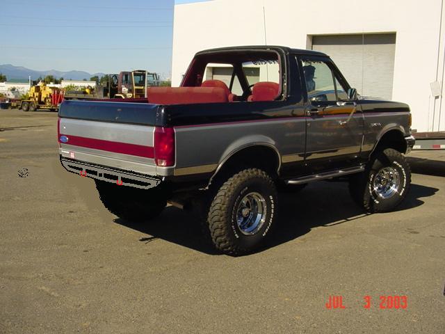 Black and silver lifted Ford Bronco, top off, red interior, rear 3/4 view