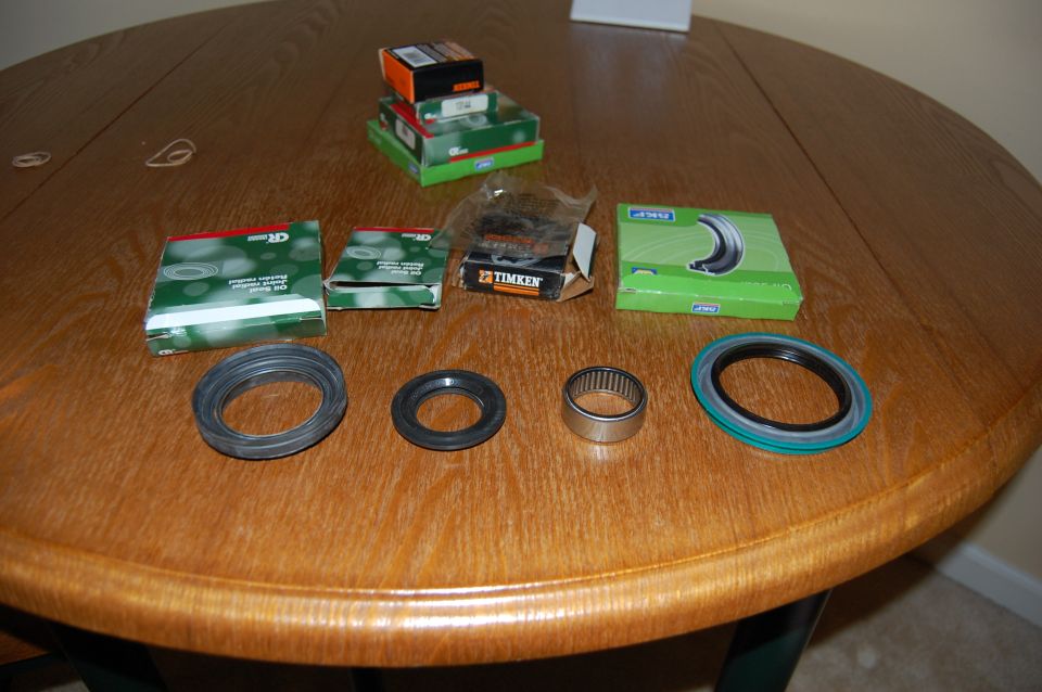 Vehicle front wheel bearings and seals laid out on a wooden table. Boxes from CR and Timken are visible