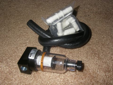 1990 Ford Bronco - A clear bowl air filter with a black hose and assorted plastic fittings are laid out on a carpeted surface.