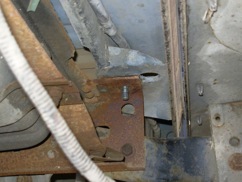 Rusty frame bracket and bolt under a vehicle