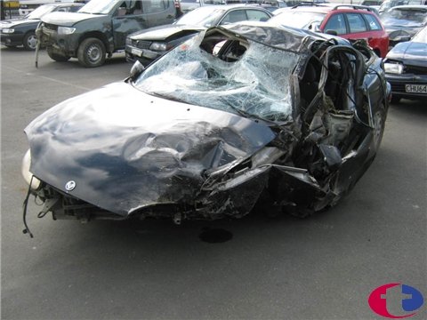 1993 Mazda MX-3 - This heavily damaged black coupe has a shattered windshield and significant body damage, suggesting a severe accident.