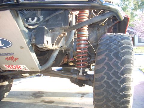 1992 Ford Ranger - Close-up of an off-road truck's suspension system, a large tire and a red coilover shock absorber. A Ford badge is visible on the skid plat…