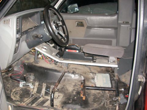 1992 Ford Ranger - The interior of a truck shows exposed wiring and a stripped floor, indicating it is undergoing modification or repair.