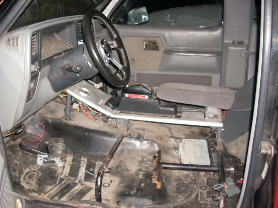 Interior of a truck with the floor stripped, showing wiring and parts of the console and steering wheel