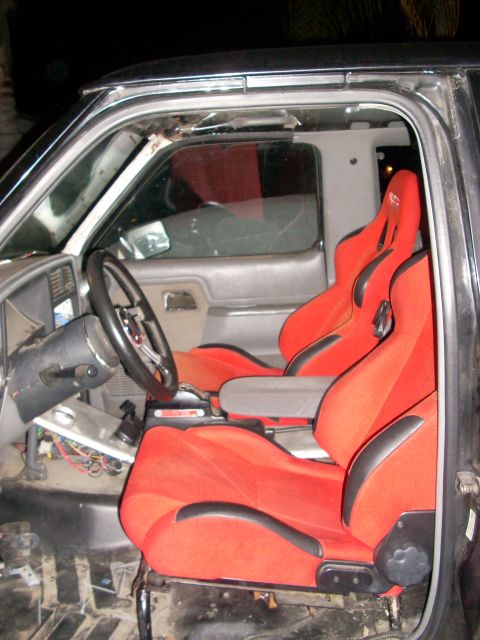 1992 Ford Ranger - The interior of a truck is shown, bright red racing seats and an aftermarket steering wheel, with exposed wiring visible.