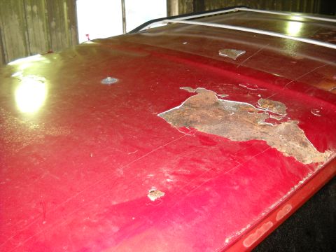 1993 Ford C-150 (Centurion Conversions) - The red roof of a vehicle displays extensive rust damage and chipped paint, indicating poor condition.