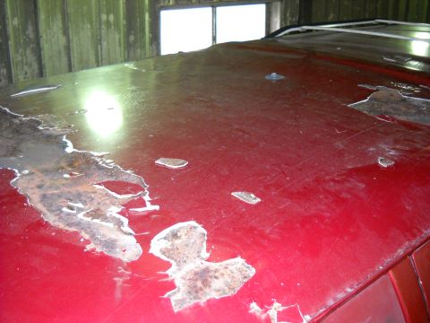 1993 Ford C-150 (Centurion Conversions) - The red roof of a vehicle displays significant rust damage and paint deterioration, indicating poor condition.