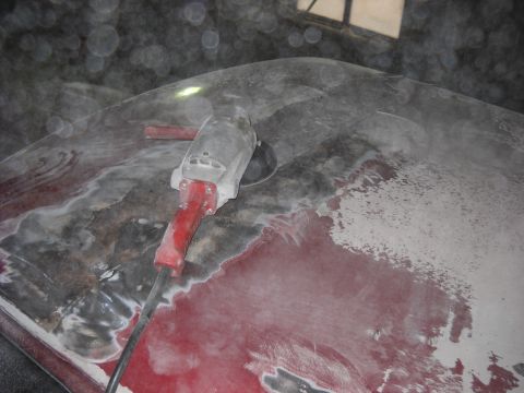1993 Ford C-150 (Centurion Conversions) - An angle grinder is being used to sand down the body of a vehicle, revealing areas of red paint and primer.