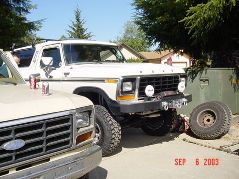 1989 Ford Bronco - A white Ford Bronco, likely from the late 1970s, is parked outdoors with a spare tire nearby.