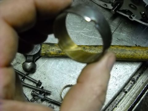 1993 Ford C-150 (Centurion Conversions) - A damaged metal ring is examined, with tools and hardware visible on a workbench.