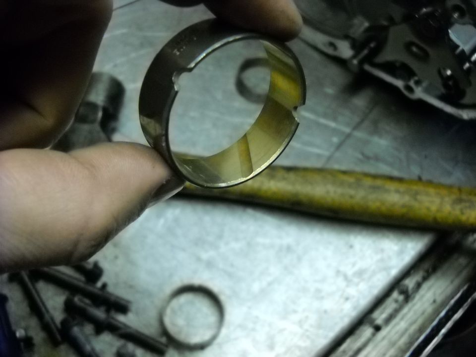 Hand holding a worn metal bearing or bushing, likely from a transmission