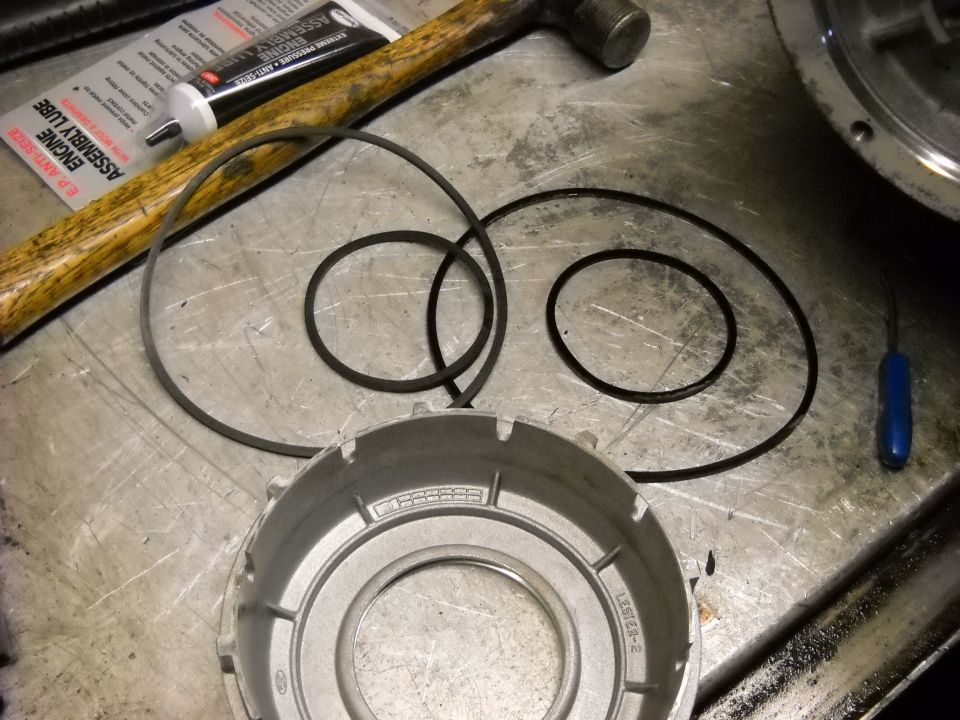 Transmission drum, O-rings, E.P. Anti-Seize engine assembly lube, and hammer on a workbench