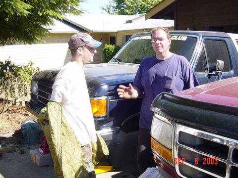 1989 Ford Bronco - Two men stand by a 1989 Ford Bronco and another Ford truck on a sunny day.