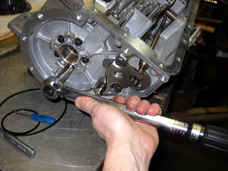 Hand using a torque wrench on a metal component of a transmission