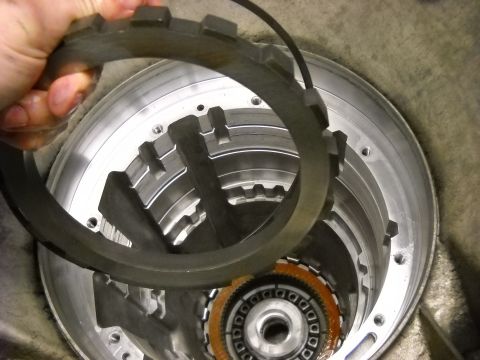 1993 Ford C-150 (Centurion Conversions) - A clutch pack ring is being held over the internal components of an automatic transmission during a rebuild.