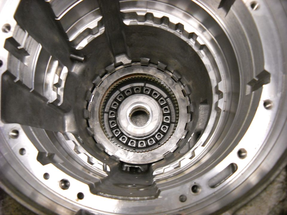 Close-up of a disassembled automatic transmission component with visible gears and metal housing