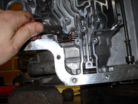 1993 Ford C-150 (Centurion Conversions) - Mechanic's hand uses pliers to adjust a spring within the transmission valve body during an E4OD rebuild.