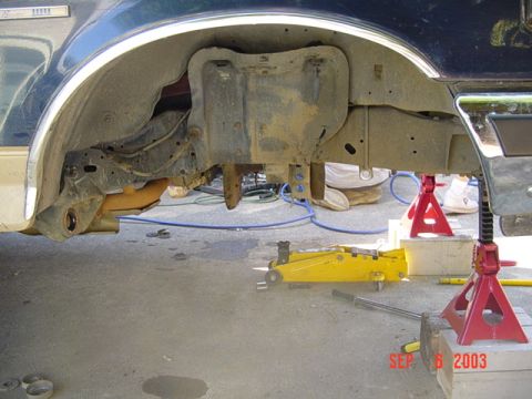 1989 Ford Bronco - The vehicle's undercarriage is visible, supported by jack stands and a hydraulic jack.