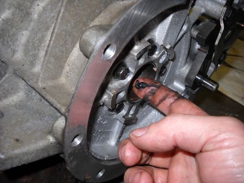 1993 Ford C-150 (Centurion Conversions) - A finger, covered in grease, interacts with a component within a vehicle's transmission assembly.