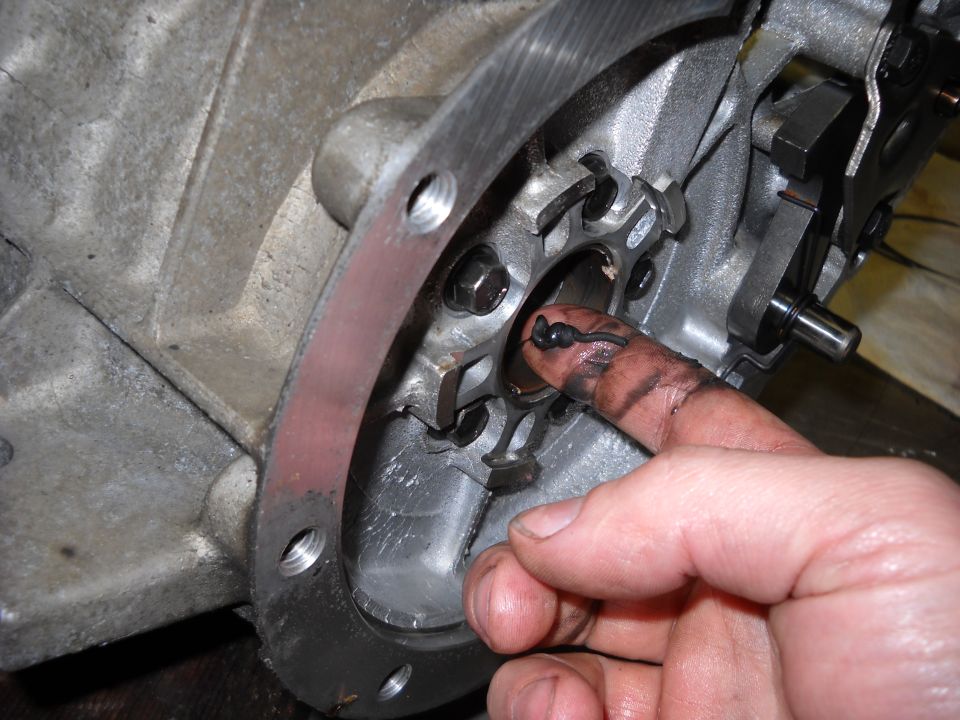 Close-up of a greasy finger touching a metal part inside a transmission housing