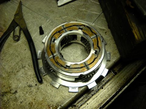 1993 Ford C-150 (Centurion Conversions) - A transmission clutch pack, disassembled with friction material and metal plates, lies on a workbench next to a pair of pliers.
