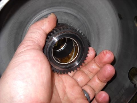 1993 Ford C-150 (Centurion Conversions) - A hand holds a gear, likely part of a transmission rebuild.