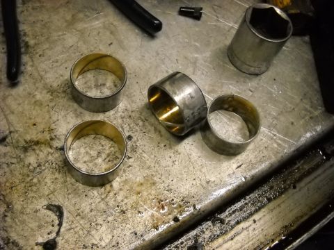 1993 Ford C-150 (Centurion Conversions) - Metal bushings and a socket wrench are on a dirty workbench, suggesting mechanical work.