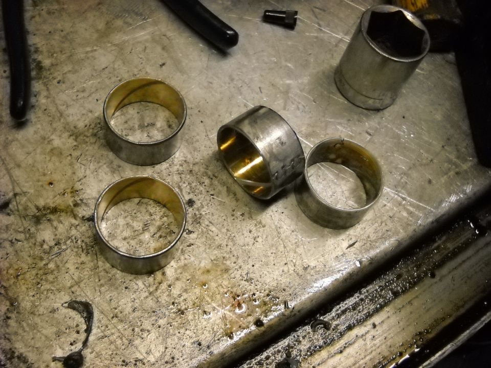 Four metal bushings and a socket wrench on a workbench