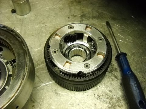1993 Ford C-150 (Centurion Conversions) - Close-up of a disassembled transmission component, likely part of an E4OD rebuild, with a screwdriver nearby.